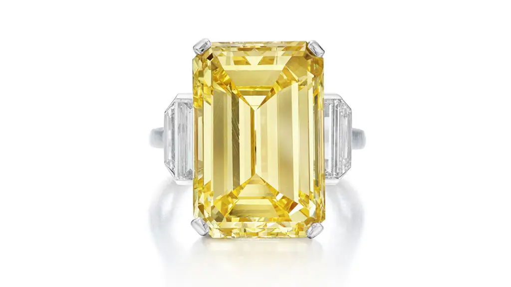 This ring featuring an emerald-cut, 18.18-carat, fancy-intense-yellow diamond between baguette and trapezoid-shaped diamonds at Sotheby's image