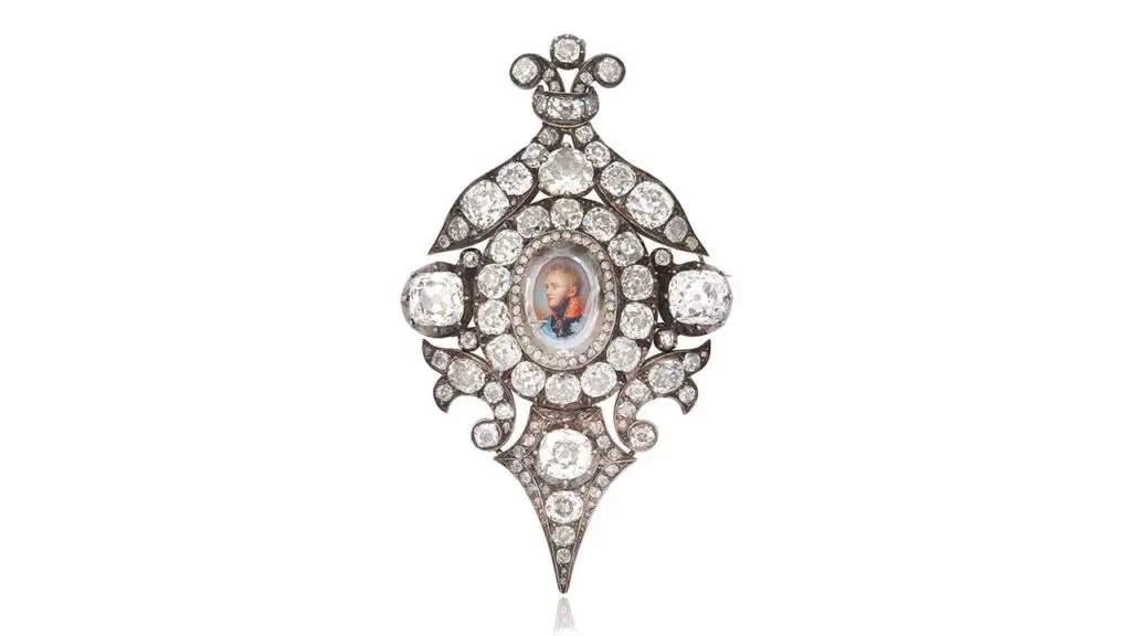 A jewel featuring a watercolor portrait of Emperor Alexander I of Russia, from around 1810, designed by Sidmouth. The portrait is topped by a portrait-cut diamond, in a closed-back rose-cut diamond setting. It was later set within a surround of old brilliant and old cushion-cut diamonds, featuring scroll and foliate motifs at Bonhams image