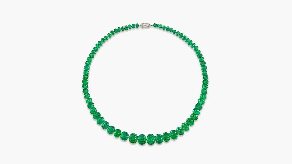 A Van Cleef & Arpels necklace featuring 72 carved Colombian emeralds beads weighing between 1.11 and 23.53 carats, with two shield-shaped diamonds on the clasp at Sotheby's image