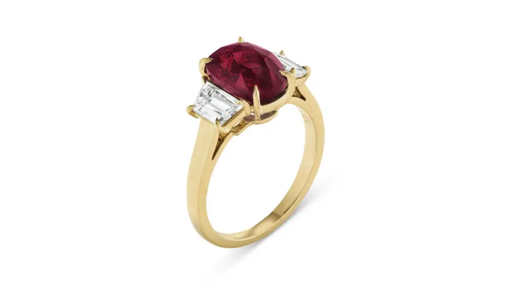 Ring containing an oval mixed-cut, Mozambican ruby between trapezoid-shaped diamonds at Christie's image