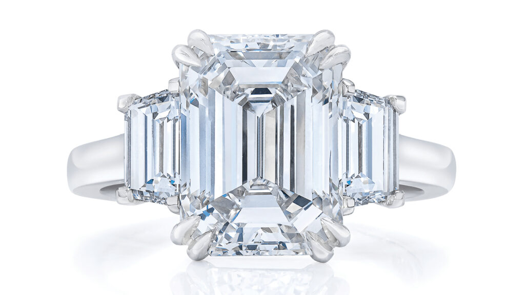 A three-stone ring centering an emerald-cut diamond image