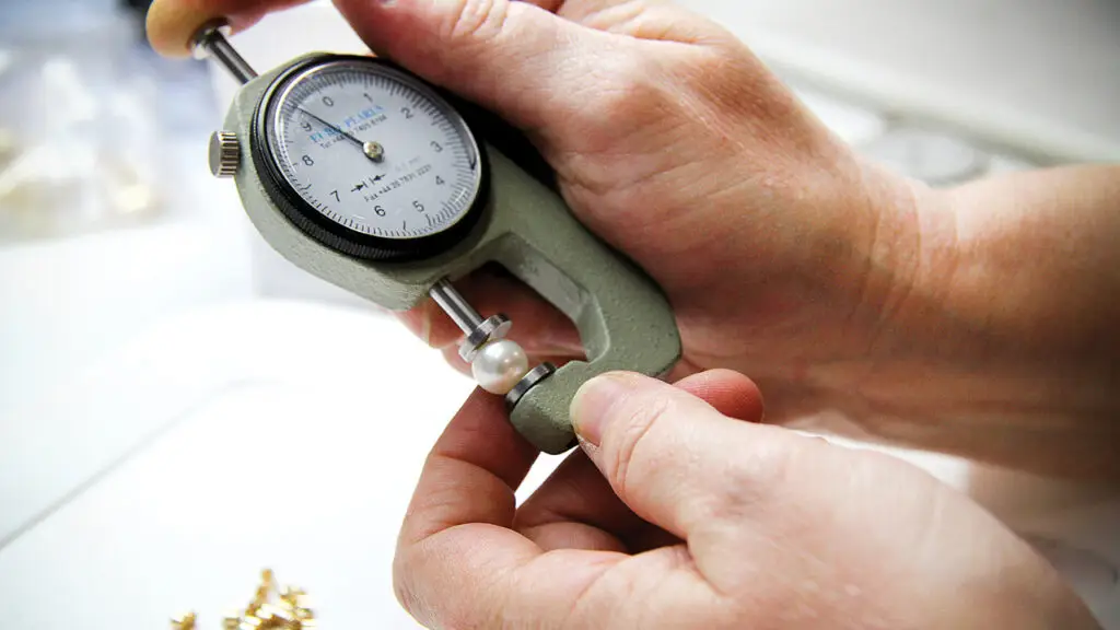 Expert at Yoko London measures a pearl to determine its diameter image