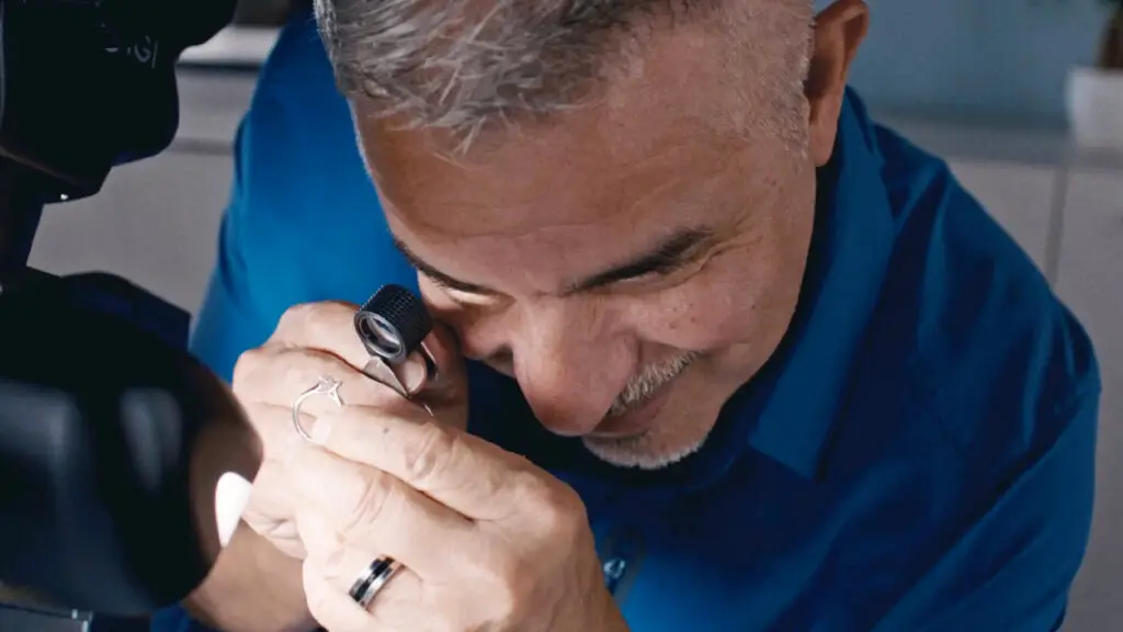 A grader looking at jewelry through a loop image