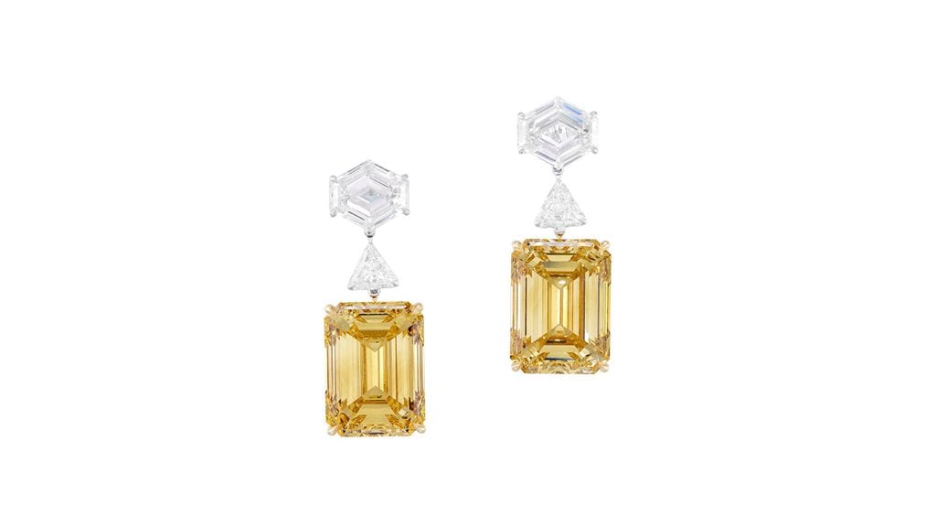 A pair of earrings featuring step-cut, fancy-brown-yellow diamonds – a 12.55-carat, VS2 and a 12.56-carat, VS1 stone – each hanging from a modified hexagonal step-cut diamond, spaced by a triangular-shaped stone at Phillips image