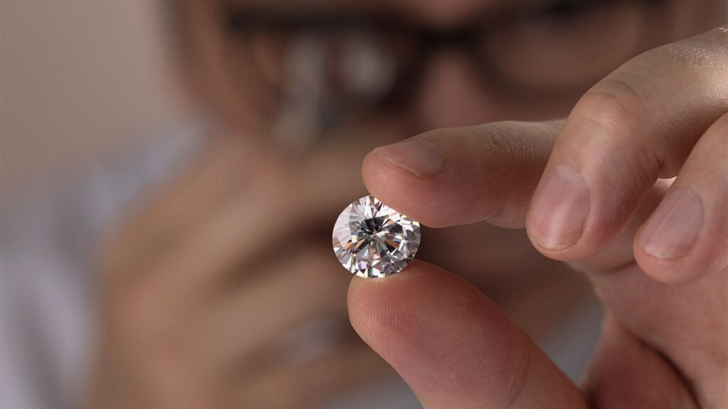 A man inspecting a polished diamond with a loupe image