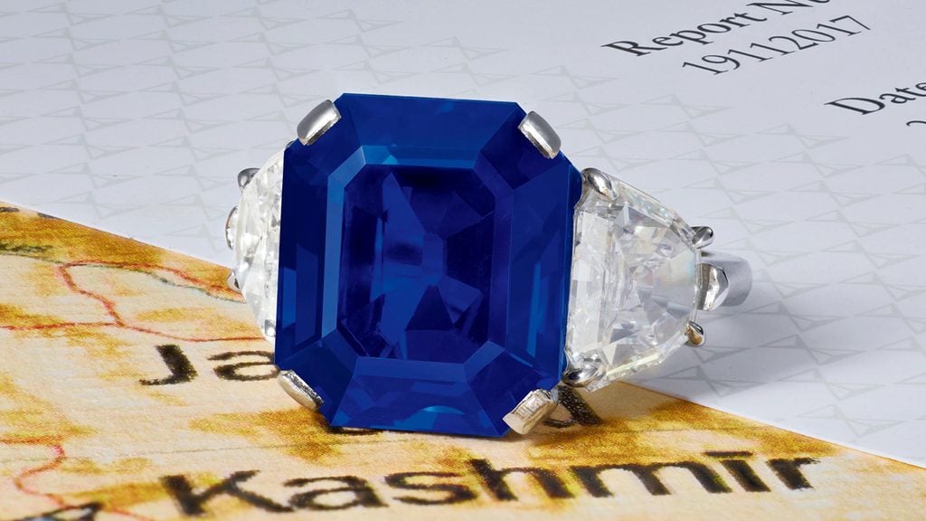 A ring centering an octagonal-shaped, 11.88-carat Kashmir sapphire between two shield-shaped diamonds at Poly Auction image