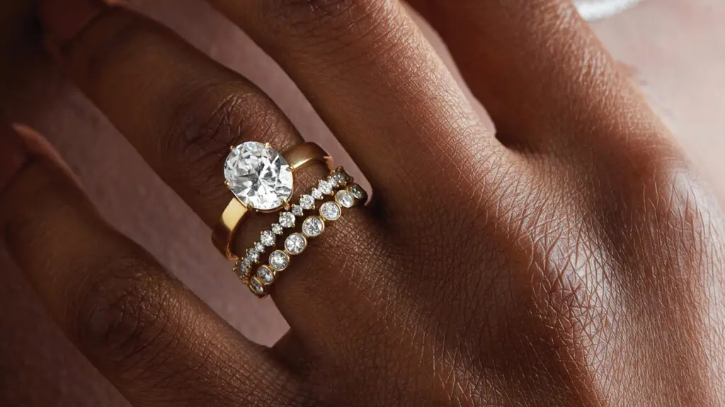 Gold and diamond engagement ring and wedding bands by Greenwich St. Jewelers on a model image