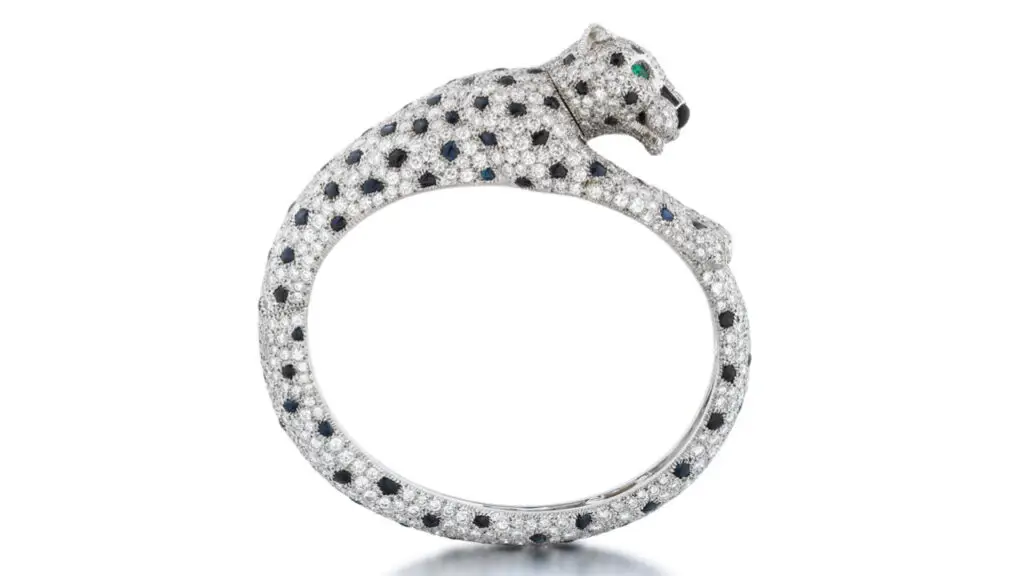 This Cartier bangle has a panther head with sapphire spots among brilliant-cut diamonds, pear-shaped emerald eyes, and a polished onyx nose by Sotheby's image