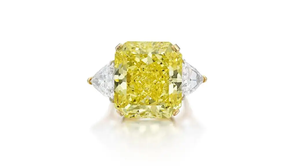 Ring featuring cut-cornered rectangular modified brilliant-cut fancy-vivid-yellow diamond flanked by triangle-shaped, D-color diamonds at Sotheby's image