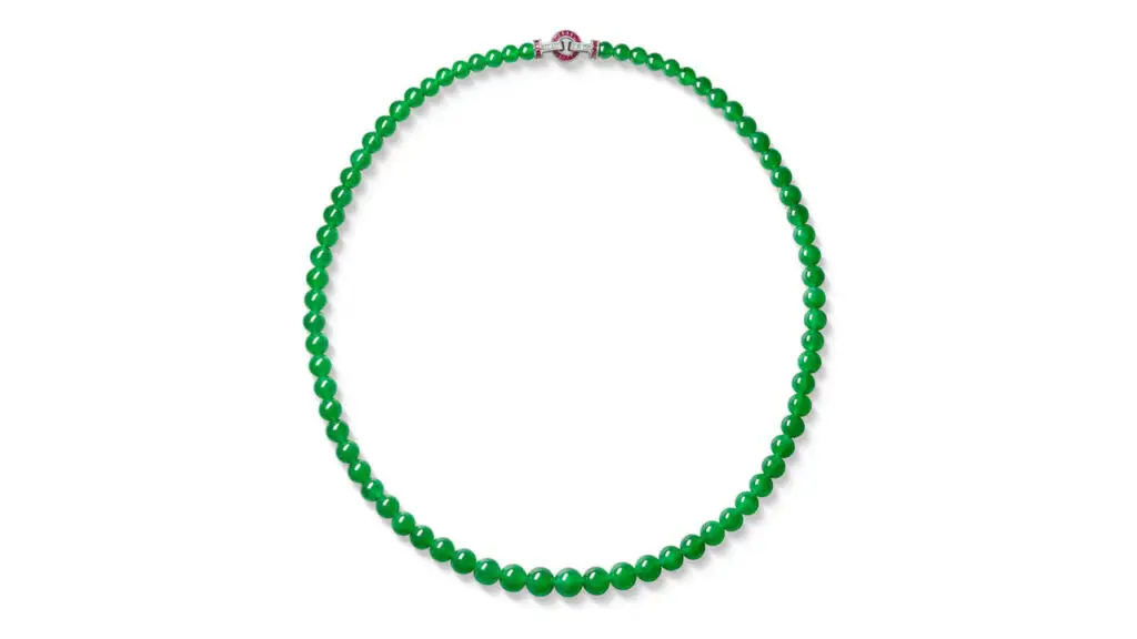 A jadeite necklace featuring 73 graduated highly translucent vivid-green beads, with a clasp boasting calibré-cut rubies and diamonds at Sotheby's image