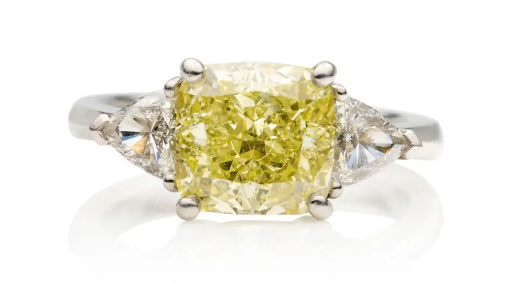 This ring features a cushion-shaped, 4.07-carat, fancy-intense-yellow, VVS1 diamond between trilliant-cut stones at Bonhams image