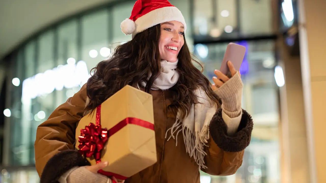 A woman carrying a holiday gift image
