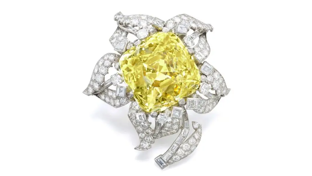 Cartier Allnatt diamond brooch containing a round-cornered square brilliant-cut fancy-vivid-yellow diamond, with diamond petals and leaves at Sotheby’s image