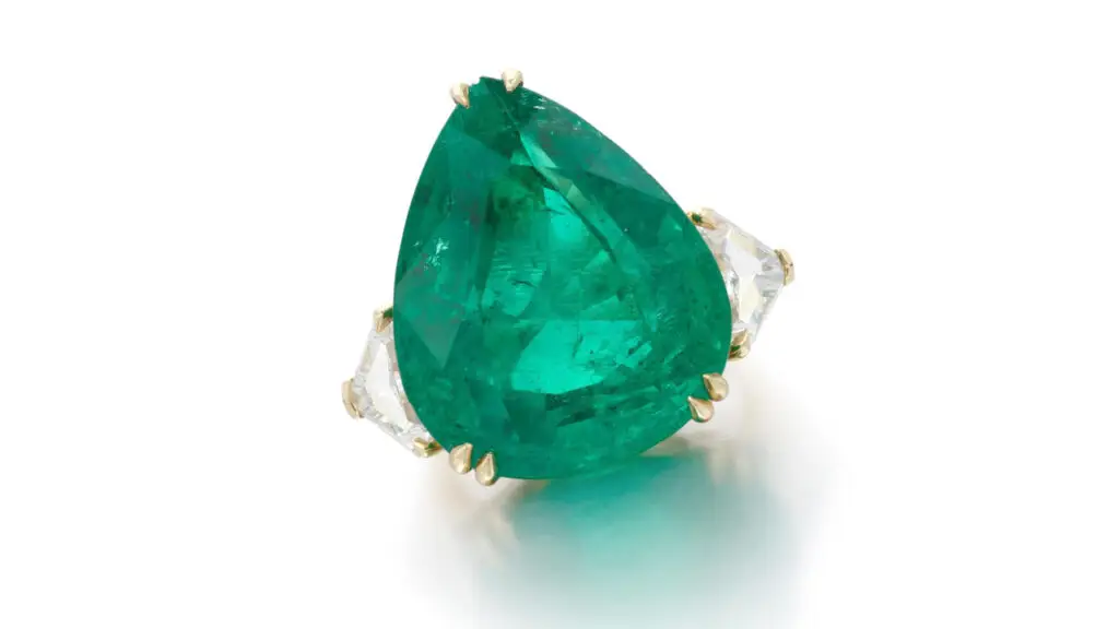 Ring with a pear-shaped Colombian emerald center stone shouldered by shield-shaped diamonds at Sotheby's image