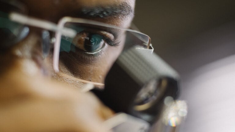 An employee at De Beers sightholder Almod Diamonds viewing a polished stone in Windhoek, Namibia with Ben Perry/Armoury Films/De Beers image
