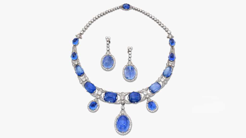 This demi-parure comprises a necklace and a pair of pendant earrings featuring a graduated series of cabochon sapphires in a frame of millegrain-set old European-cut diamonds, with single- and rose-cut diamonds. It was formerly in the collection of Sibylla of Saxe-Coburg and Gotha, Duchess of Vasterbotten at Sotheby's image