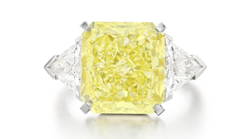A Cartier ring bearing a radiant-cut, 8.67-carat, fancy-intense-yellow, VVS1 diamond between two triangular stones at Sotheby's image